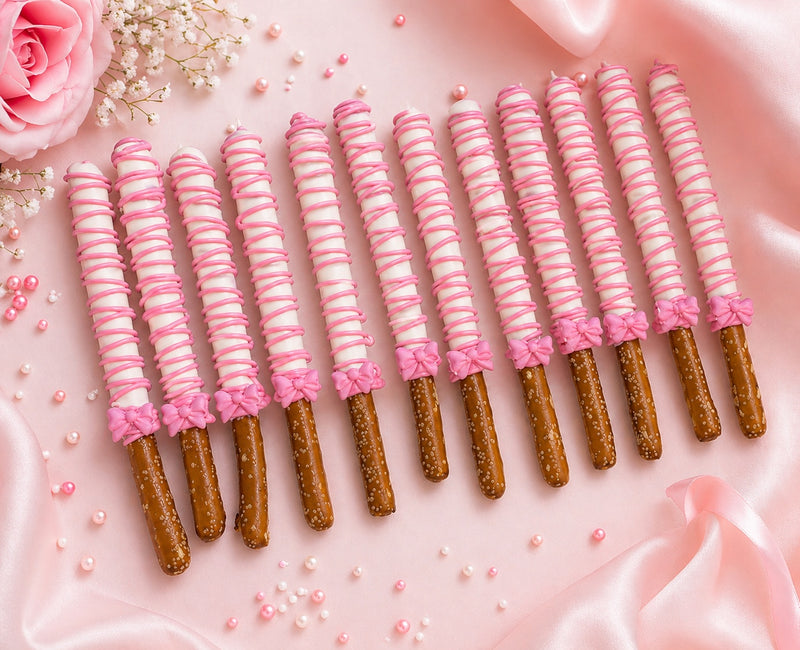 Chocolate-covered pretzel rods decorated with pink drizzle and bows